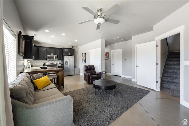 living area featuring baseboards, stairway, a ceiling fan, and recessed lighting