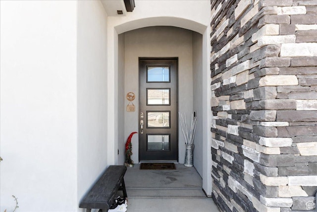 property entrance featuring stone siding and stucco siding