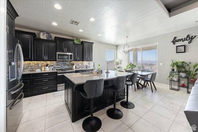 kitchen featuring light countertops, visible vents, appliances with stainless steel finishes, a sink, and dark cabinetry