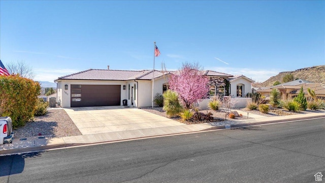 view of front facade featuring driveway, an attached garage, a tiled roof, and stucco siding