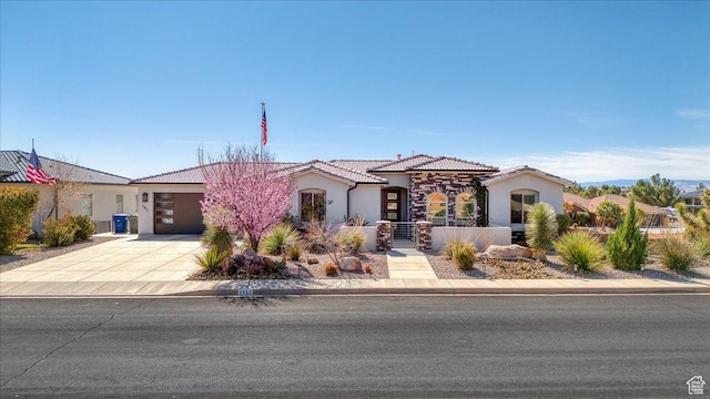 mediterranean / spanish home with driveway, a garage, a fenced front yard, a tile roof, and stucco siding