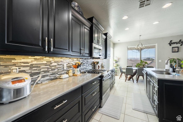 kitchen featuring tasteful backsplash, visible vents, appliances with stainless steel finishes, a sink, and dark cabinetry