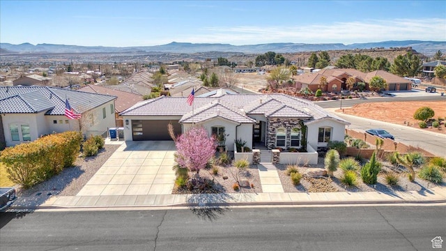 mediterranean / spanish house featuring a fenced front yard, concrete driveway, a tile roof, and a mountain view