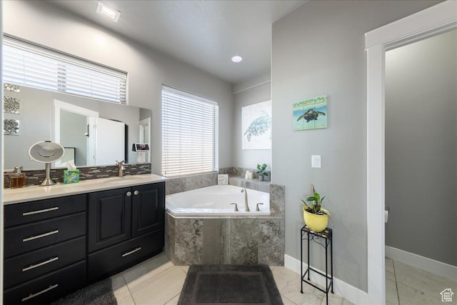 bathroom featuring tile patterned floors, vanity, baseboards, and a bath