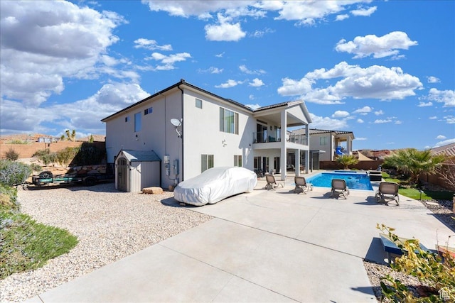 rear view of house featuring a patio, a balcony, fence, a fenced in pool, and stucco siding