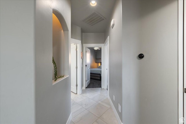 corridor featuring arched walkways, visible vents, and baseboards