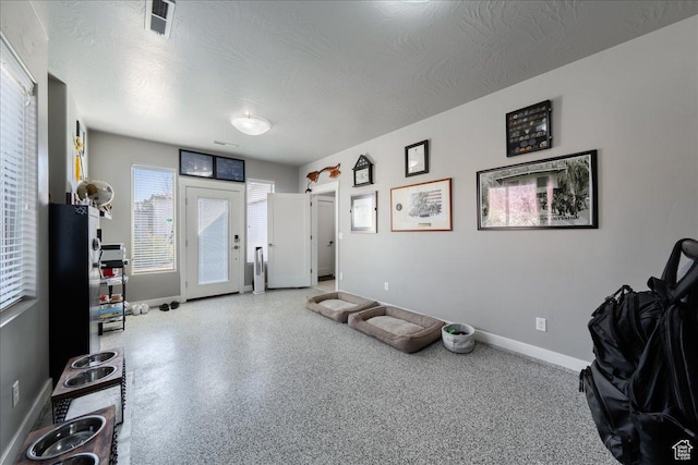 misc room with visible vents, a textured ceiling, baseboards, and speckled floor