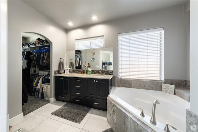 full bath featuring a walk in closet, double vanity, a sink, tile patterned flooring, and a bath