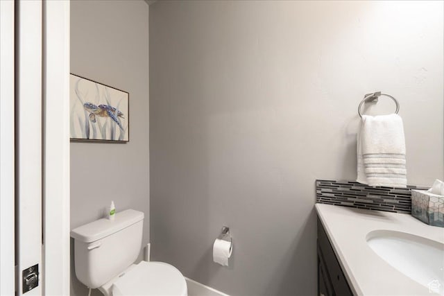 bathroom with toilet, vanity, and decorative backsplash