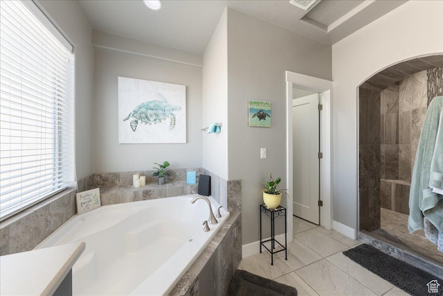 full bath with a garden tub and a tile shower
