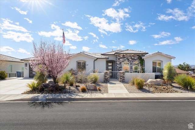 mediterranean / spanish home featuring concrete driveway, a fenced front yard, a tile roof, an attached garage, and stucco siding