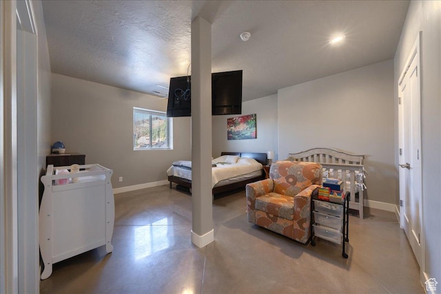 bedroom featuring finished concrete floors, baseboards, and a textured ceiling