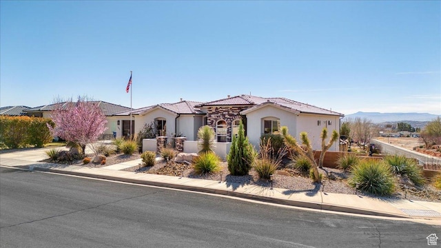 mediterranean / spanish-style house with a fenced front yard, a tile roof, and stucco siding