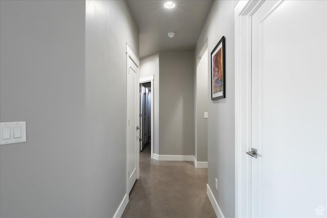 hallway featuring concrete floors and baseboards