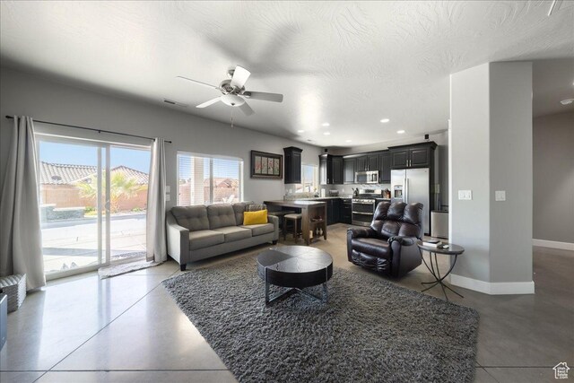 living area with recessed lighting, visible vents, a ceiling fan, a textured ceiling, and baseboards