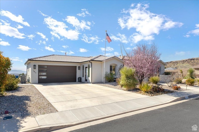 view of front facade featuring a garage, concrete driveway, a tile roof, and stucco siding