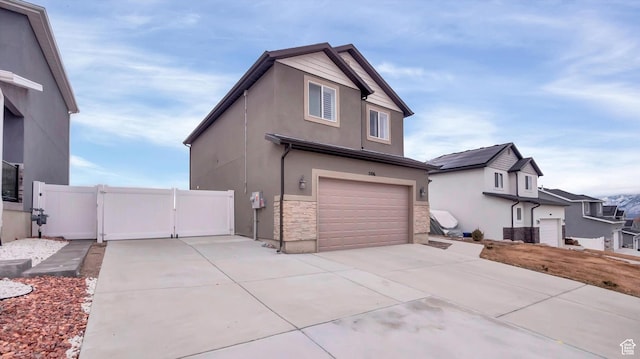 view of home's exterior with stone siding, a gate, driveway, and an attached garage