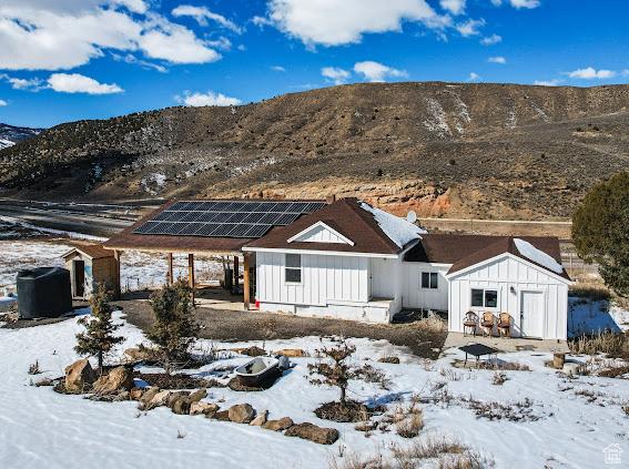 view of front of house with board and batten siding, solar panels, an outbuilding, a shed, and a carport