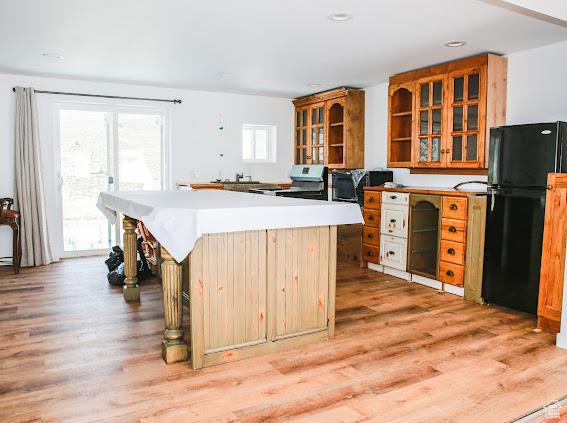 1290 Echo Crk Unit 2, Echo, UT 84024 - kitchen with a center island, brown cabinets, light wood finished floors, glass insert cabinets, and freestanding refrigerator