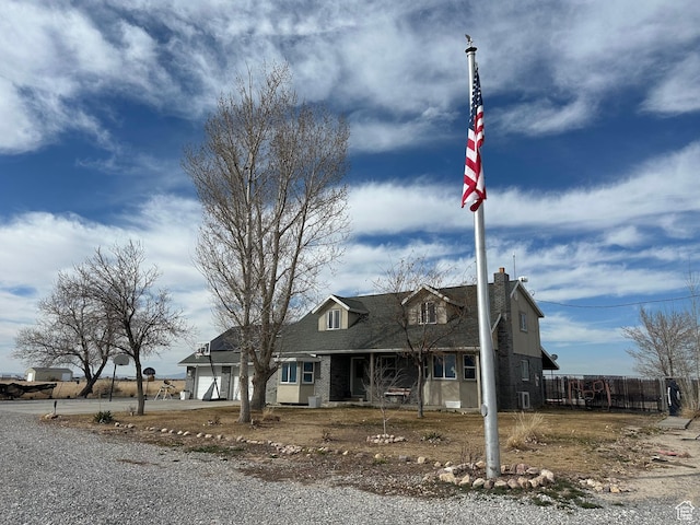 cape cod home with a porch, driveway, a chimney, a garage, and fence