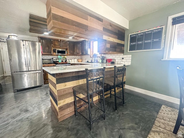 kitchen featuring backsplash, appliances with stainless steel finishes, and concrete floors