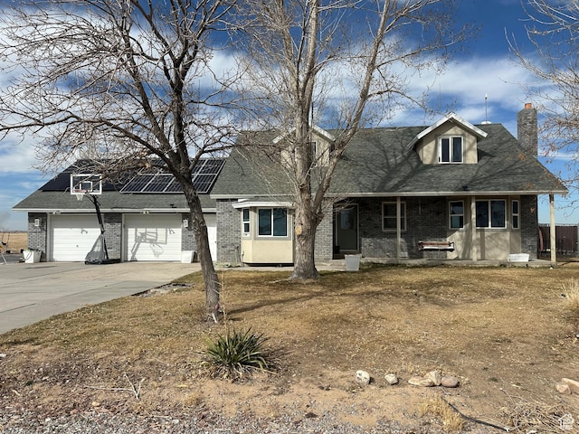 view of front of house featuring covered porch, a chimney, brick siding, concrete driveway, and solar panels