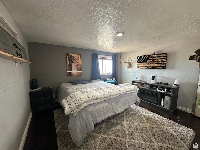 bedroom with a textured ceiling, baseboards, and wood finished floors