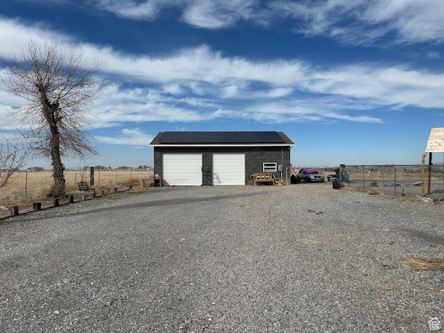 detached garage featuring fence and solar panels