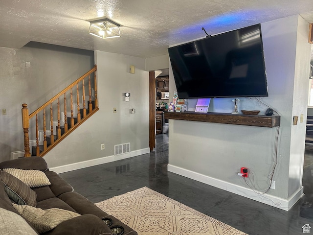 living room featuring a textured ceiling, visible vents, concrete flooring, baseboards, and stairs