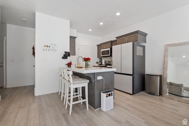4758 E Hidden Loop Rd, Eagle Mountain, UT 84005 - kitchen featuring a peninsula, white appliances, light countertops, light wood-type flooring, and a kitchen bar