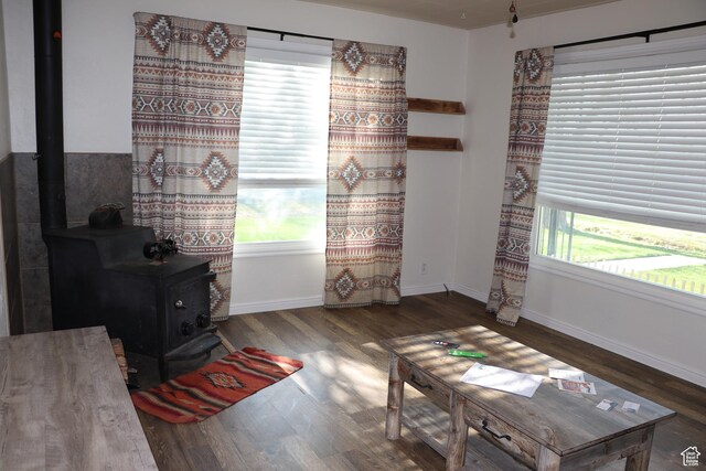 sitting room with a wood stove, wood finished floors, and baseboards