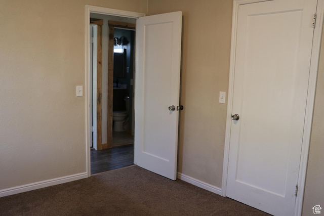 unfurnished bedroom featuring dark carpet and baseboards