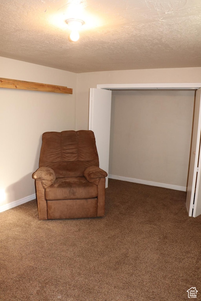 living area featuring carpet flooring, a textured ceiling, and baseboards