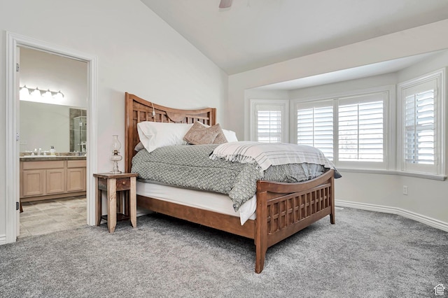 bedroom featuring light colored carpet, a sink, lofted ceiling, and ensuite bath