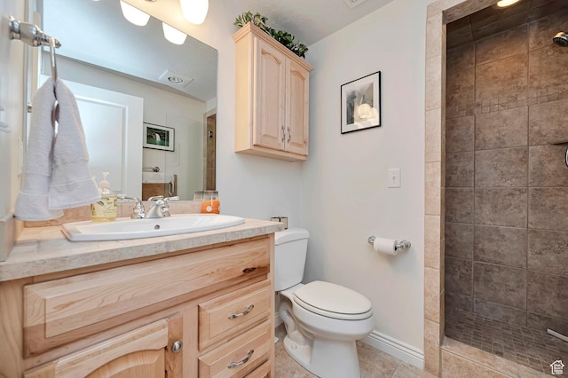 bathroom with vanity, tile patterned floors, toilet, and tiled shower