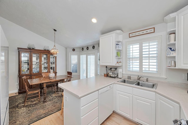 kitchen featuring white dishwasher, open shelves, a sink, white cabinets, and a peninsula
