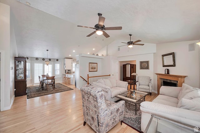 living area with light wood-style floors, ceiling fan, and lofted ceiling
