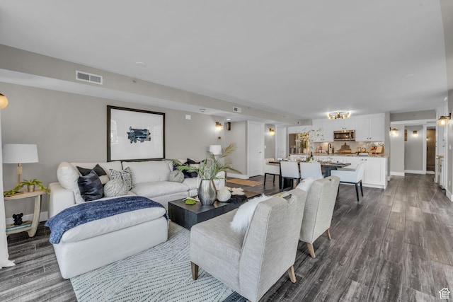 living room with baseboards, visible vents, and dark wood-style flooring
