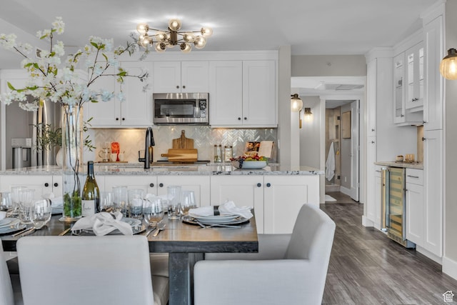 kitchen featuring tasteful backsplash, wine cooler, stainless steel microwave, and white cabinets