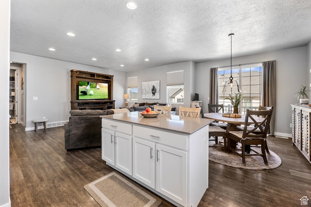 1879 N 925 E, North Ogden, UT 84414 - kitchen with a textured ceiling, dark wood-style floors, white cabinetry, a center island, and baseboards