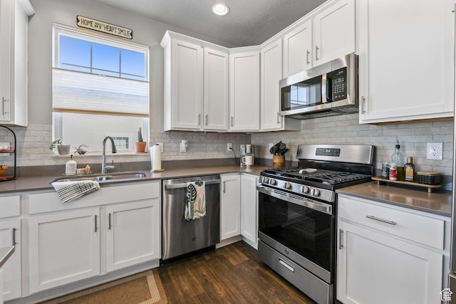 1879 N 925 E, North Ogden, UT 84414 - kitchen with appliances with stainless steel finishes, a sink, white cabinetry, dark wood-style floors, and tasteful backsplash