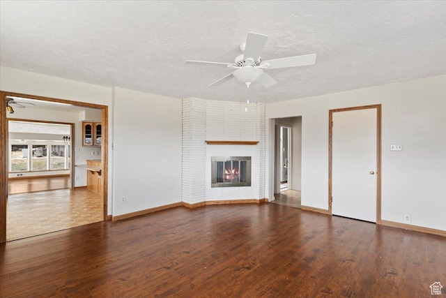445 W 5100 S, Washington Terrace, UT 84405 - unfurnished living room featuring a brick fireplace, baseboards, wood finished floors, a textured ceiling, and a ceiling fan