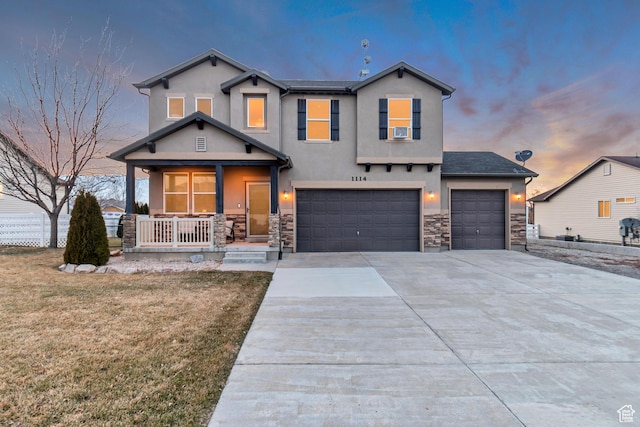 view of front of house featuring covered porch, stone siding, driveway, and stucco siding