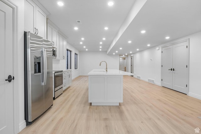 kitchen featuring a center island with sink, visible vents, appliances with stainless steel finishes, light wood-style floors, and white cabinets