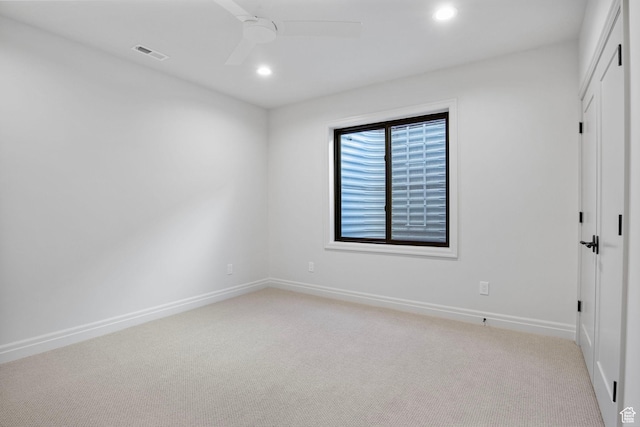empty room with light colored carpet, ceiling fan, visible vents, and baseboards