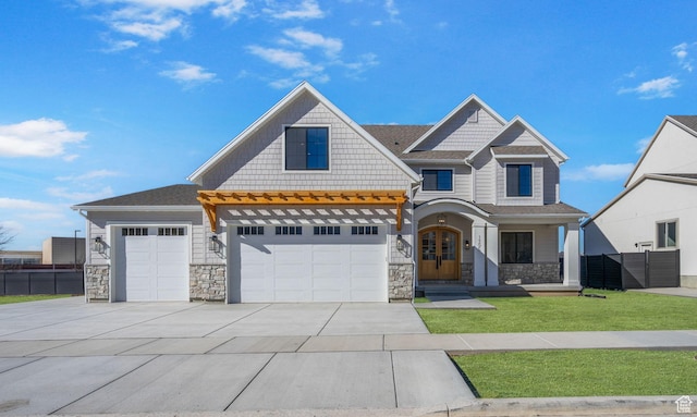 view of front facade featuring driveway, stone siding, fence, french doors, and a front yard