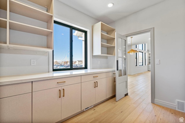 kitchen featuring light countertops, light wood-type flooring, a healthy amount of sunlight, and open shelves