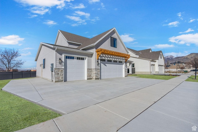view of property exterior featuring a yard, stone siding, driveway, and an attached garage