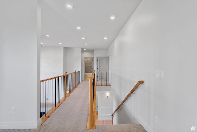 corridor featuring recessed lighting, baseboards, and an upstairs landing