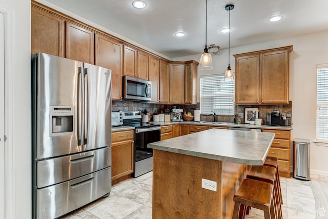 kitchen featuring stainless steel appliances, tasteful backsplash, hanging light fixtures, a kitchen island, and a sink